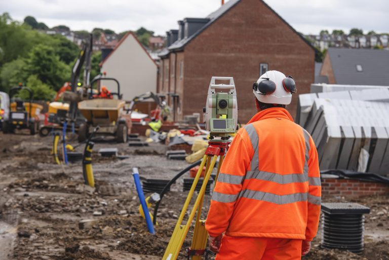 Close-up,Of,Construction,Surveyor,Working,On,Site,With,Excavator,And